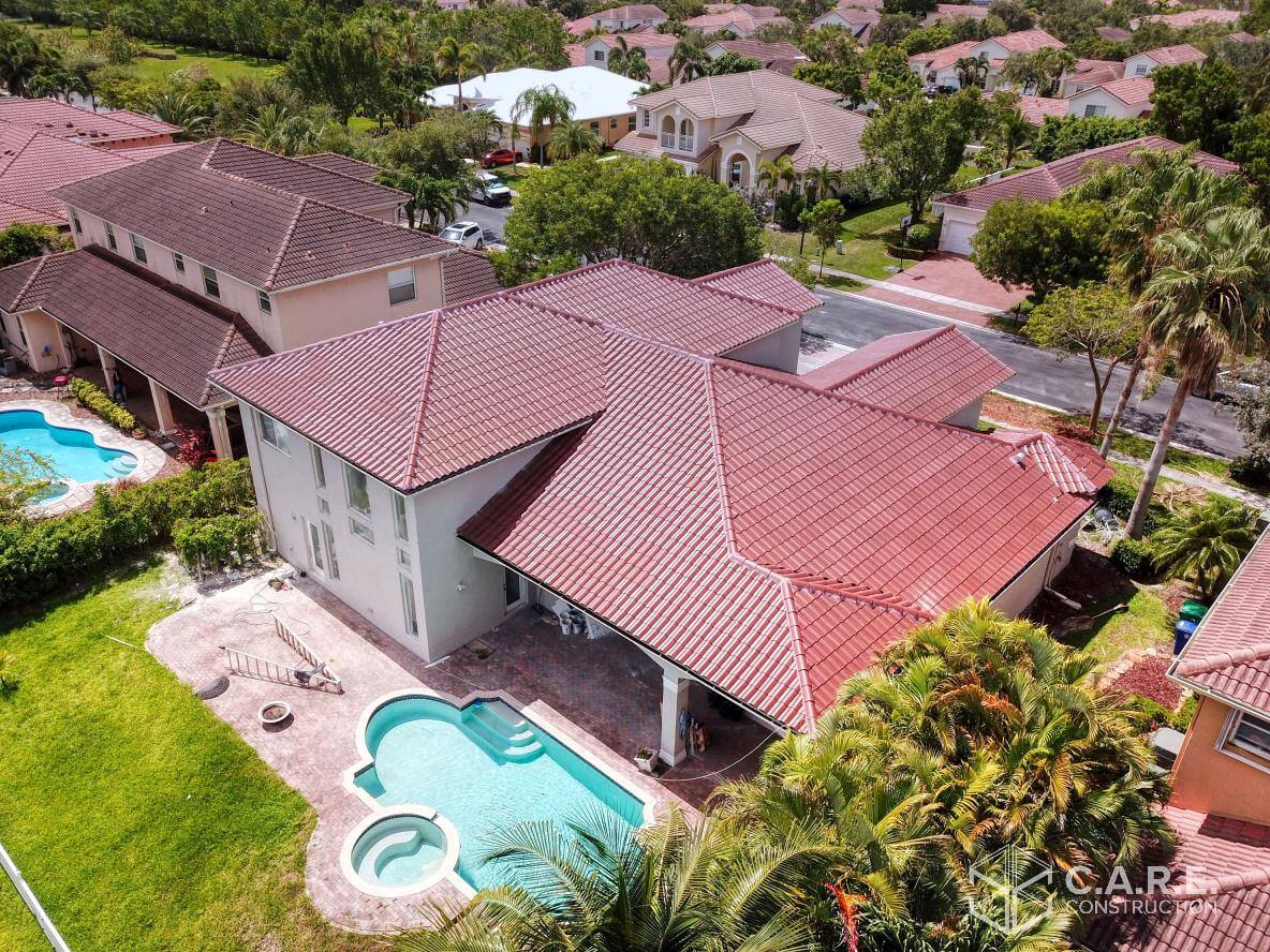 An aerial view of a house with a pool in a residential area.