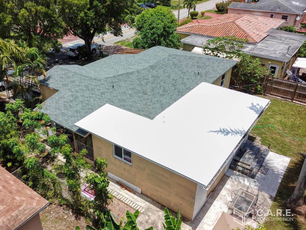 An aerial view of a house with a green roof and a white roof.