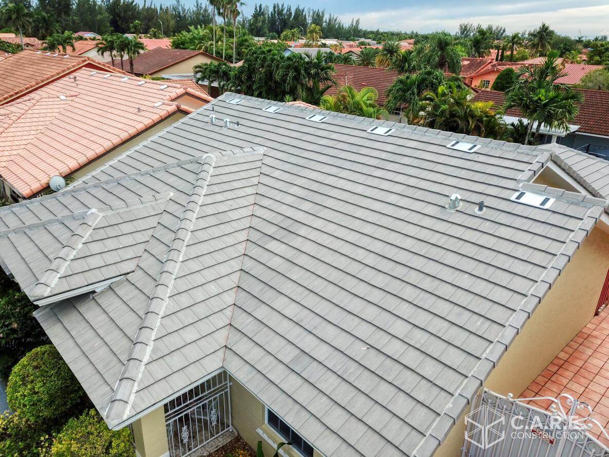 An aerial view of a house with a tiled roof surrounded by trees.