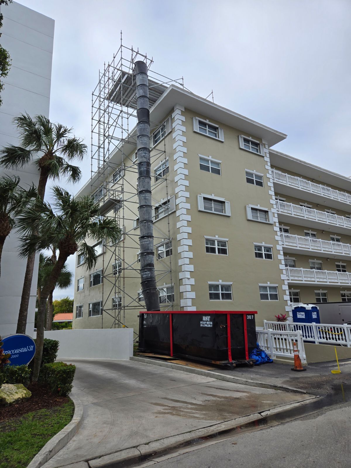 A large building with scaffolding around it is being painted.