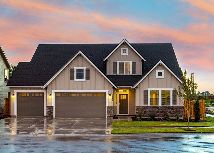 A large house with two garage doors and a driveway in front of it.