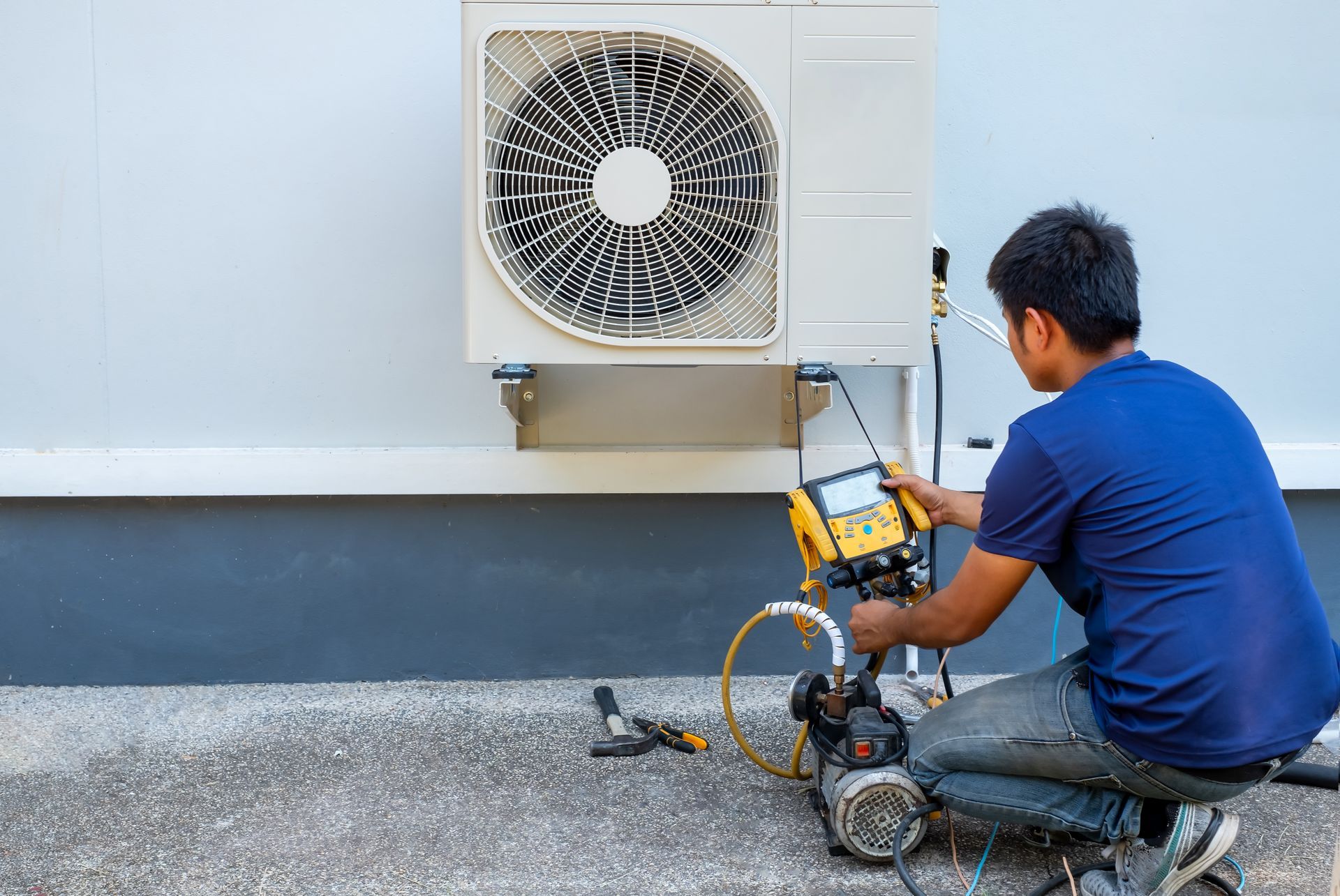 A professional HVAC technician servicing an air conditioning unit at a Hawaii rental home, ensuring peak cooling efficiency for tenants.