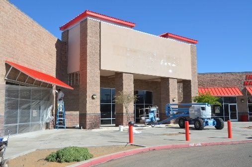 A large brick building with a red awning is being painted