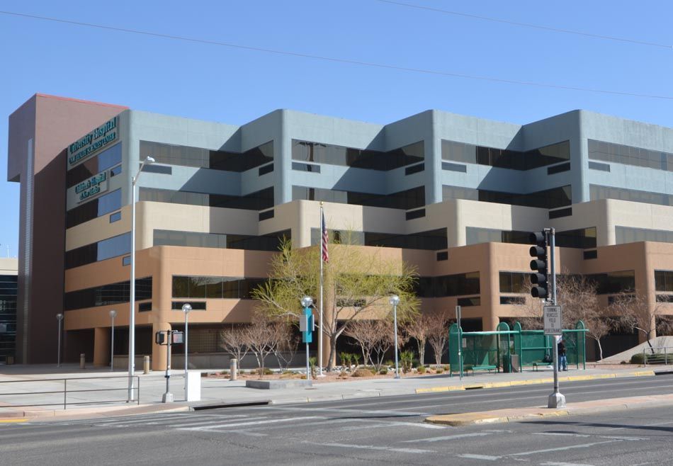 A large building with a lot of windows is on the corner of a street