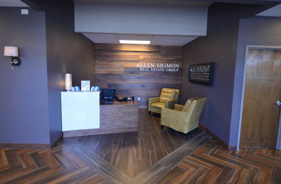 A lobby with a desk , chairs , and a wooden wall.