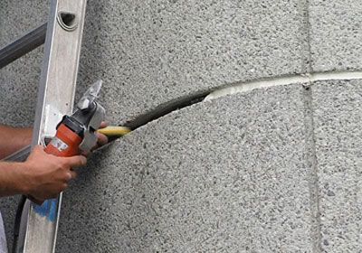 A person is using a grinder to cut a hole in a wall.
