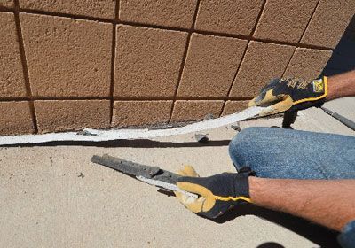 A man is sitting on the ground holding a pair of pliers.