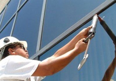 A man wearing a hard hat is working on a building.