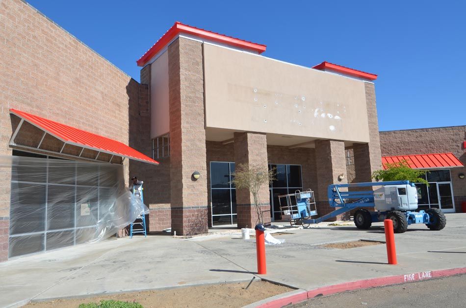 A large brick building with a red awning is being painted