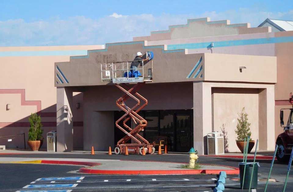 A man on a scissor lift paints the outside of a building