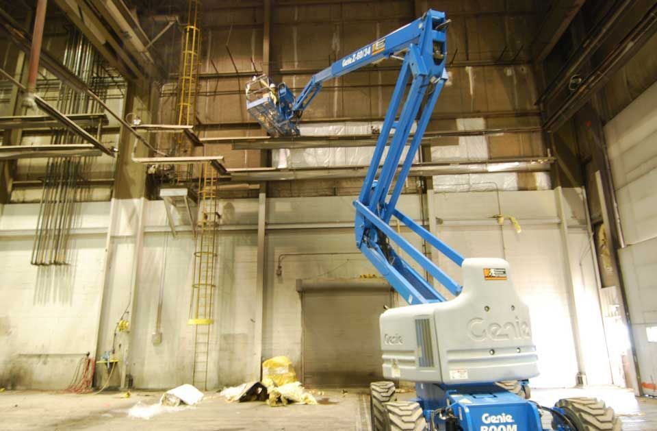 A blue genie lift is in a large warehouse.