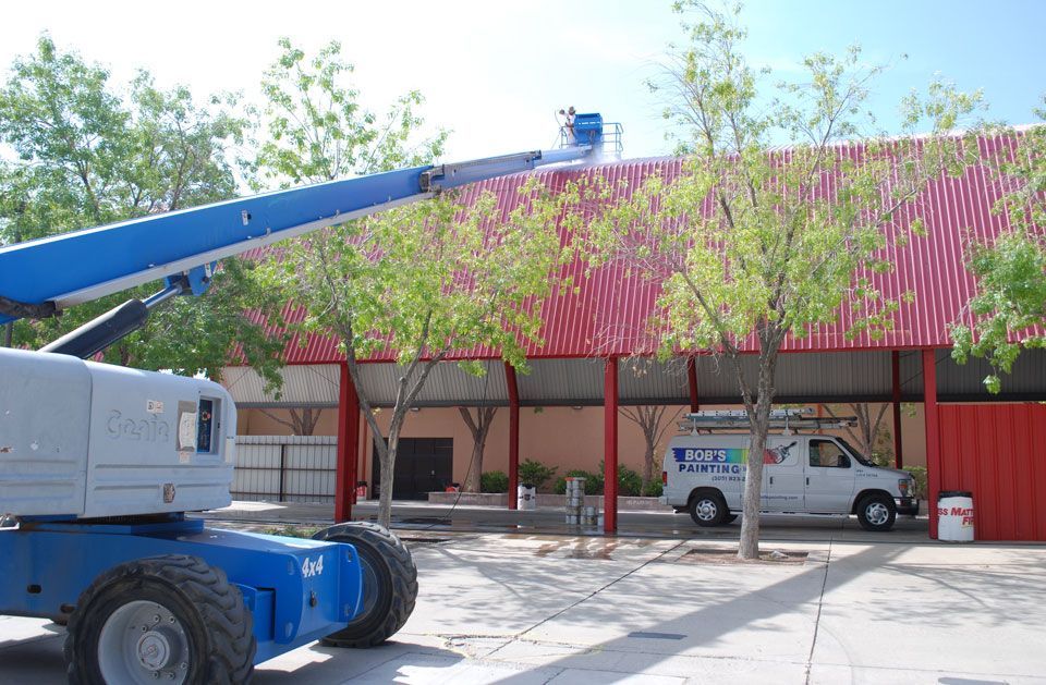 A blue crane is sitting in front of a red building.