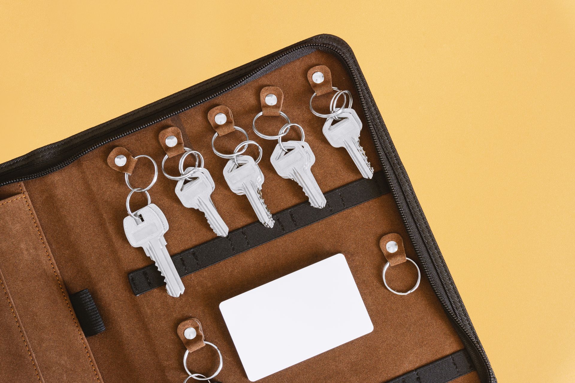 A wallet filled with keys and a card on a yellow background.