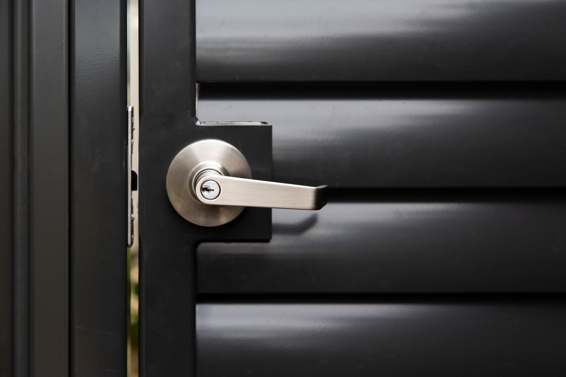 A close up of a door handle on a black door.