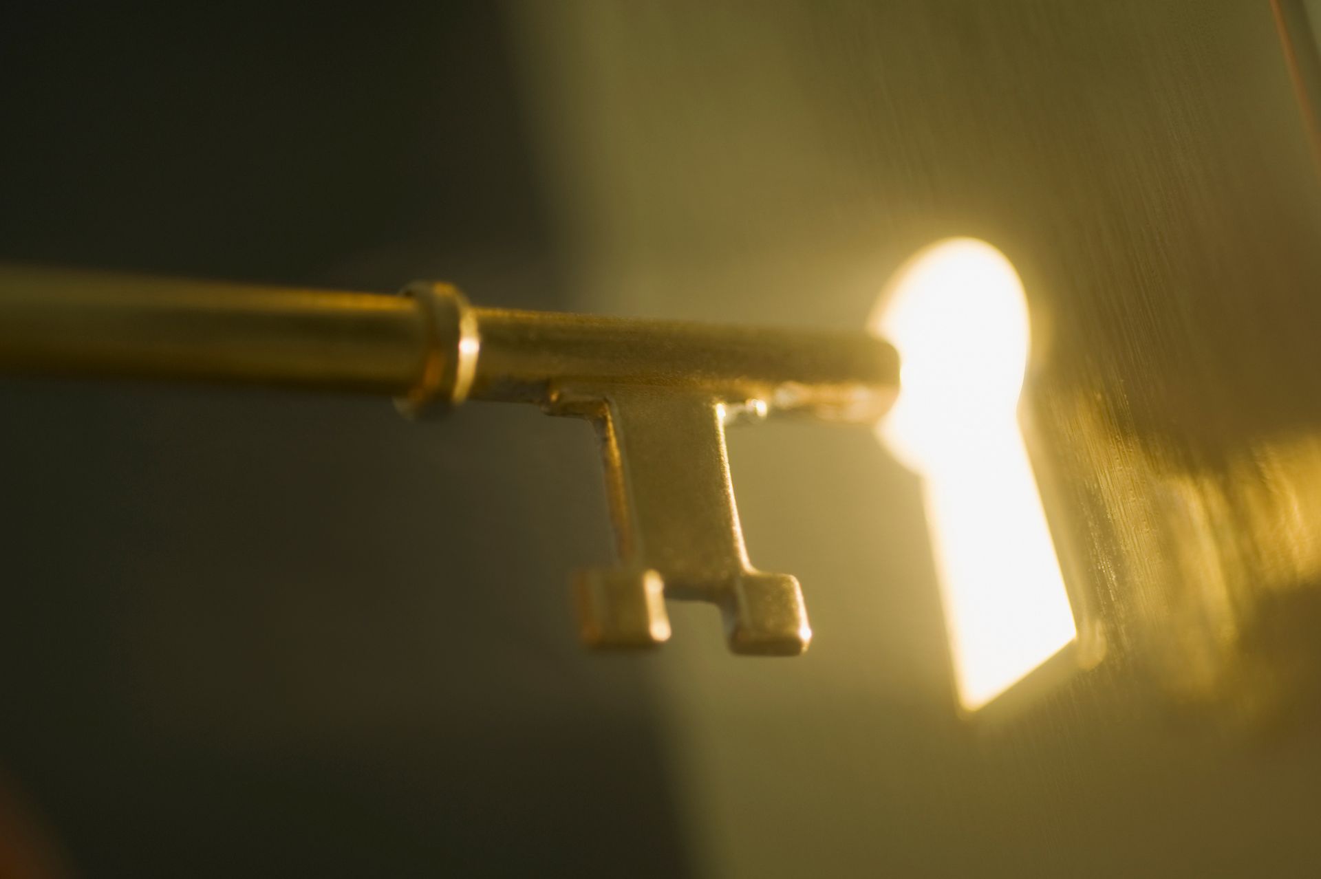 A close up of a key in a keyhole with light coming out of it.