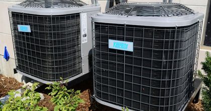 Two air conditioners are sitting next to each other on the side of a building.