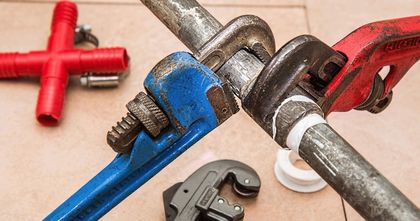 A couple of pipe wrenches sitting on top of a pipe.