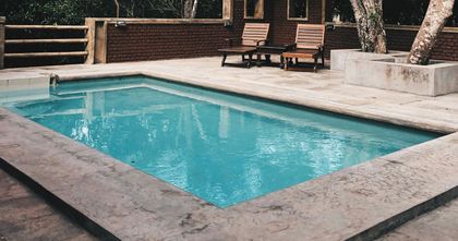 A large swimming pool with chairs and a table in the background.