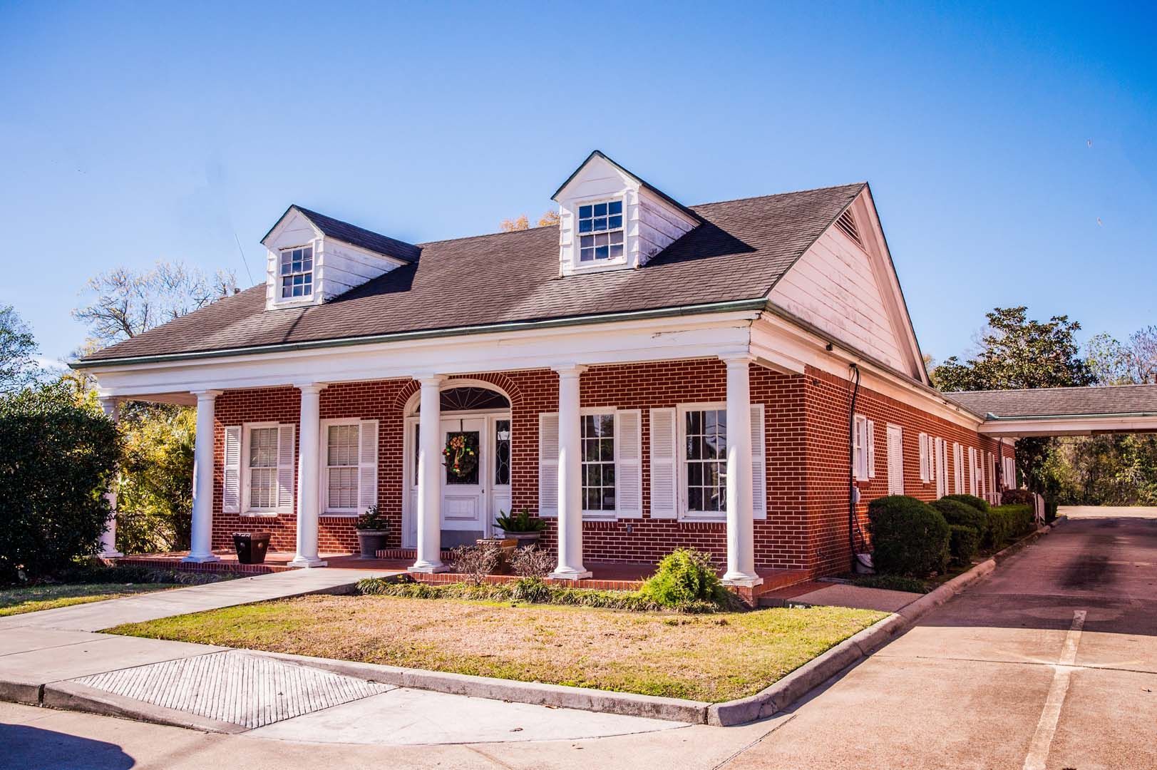 a large brick house with a white porch and a driveway .