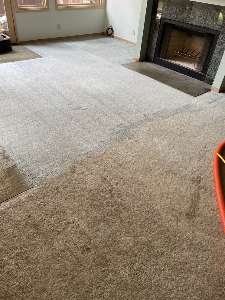 A man is cleaning a couch with a vacuum cleaner.