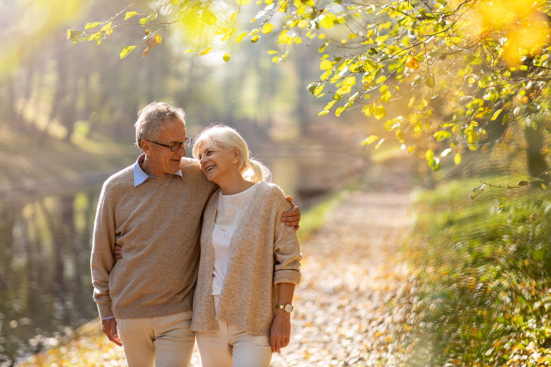 An elderly couple is walking in the woods.