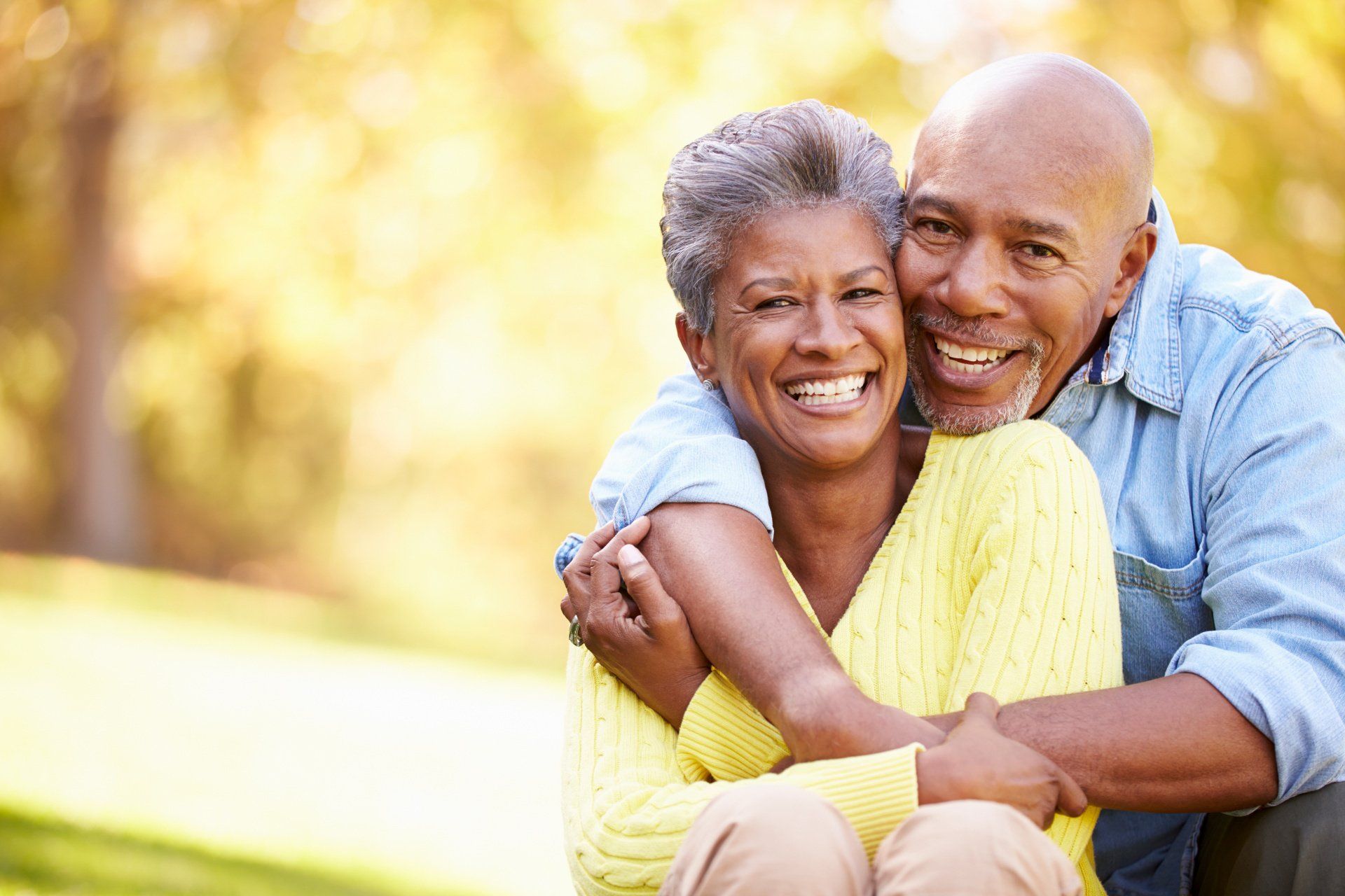 A man and woman are hugging each other in a park.