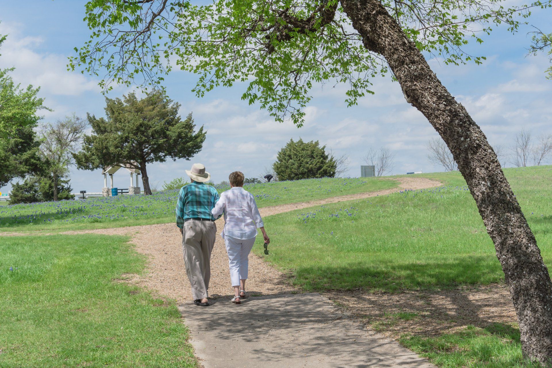 A man and a woman are walking down a path in a park.