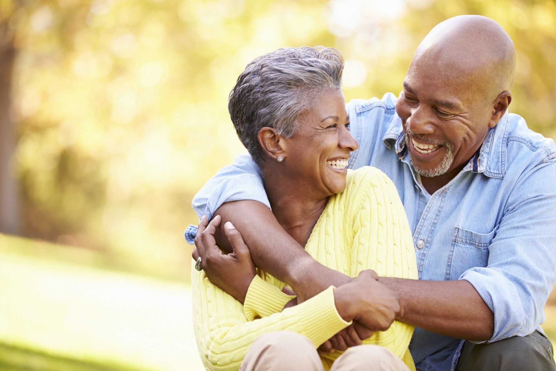 A man and a woman are hugging each other in a park.