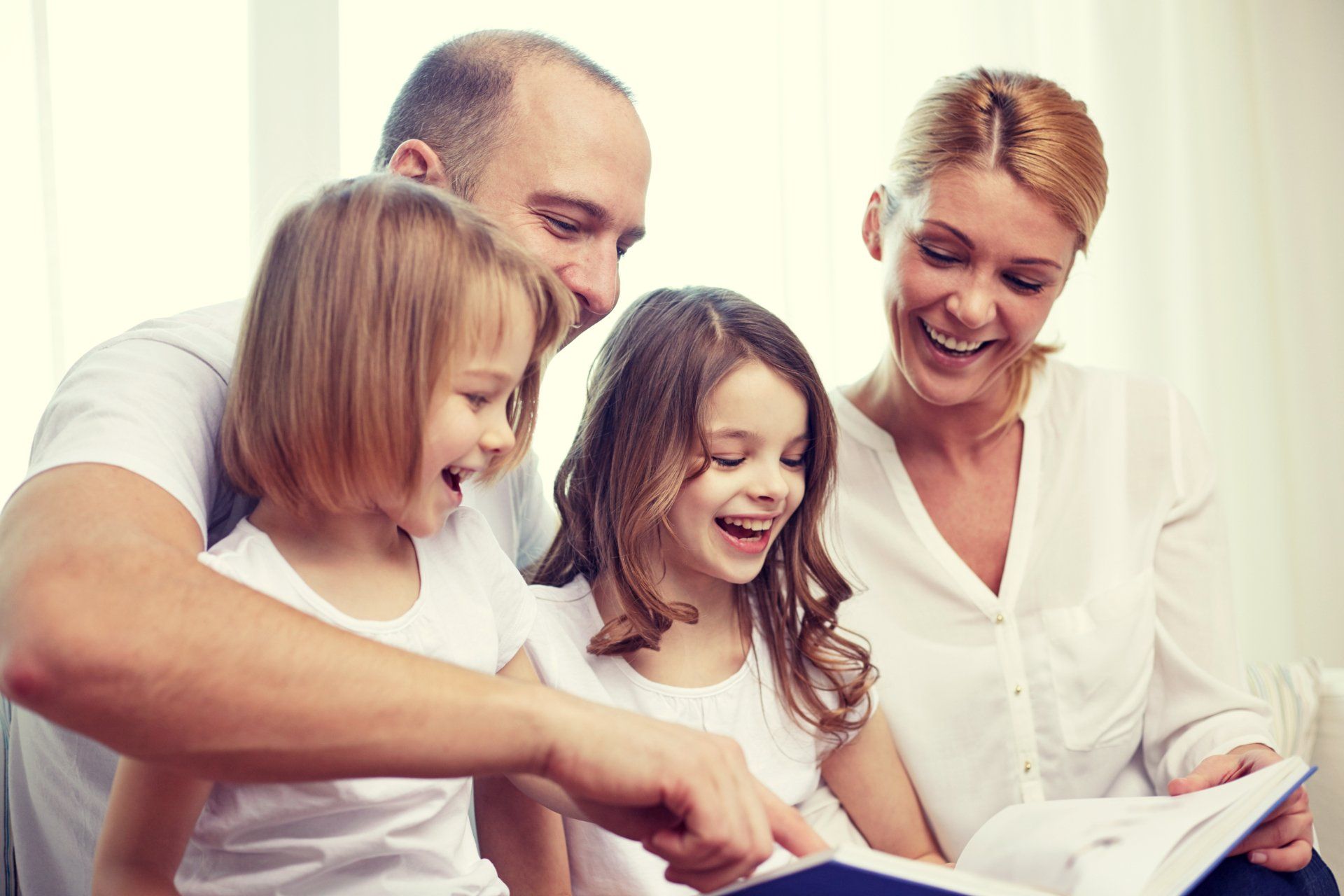 A family is sitting on a couch reading a book together.