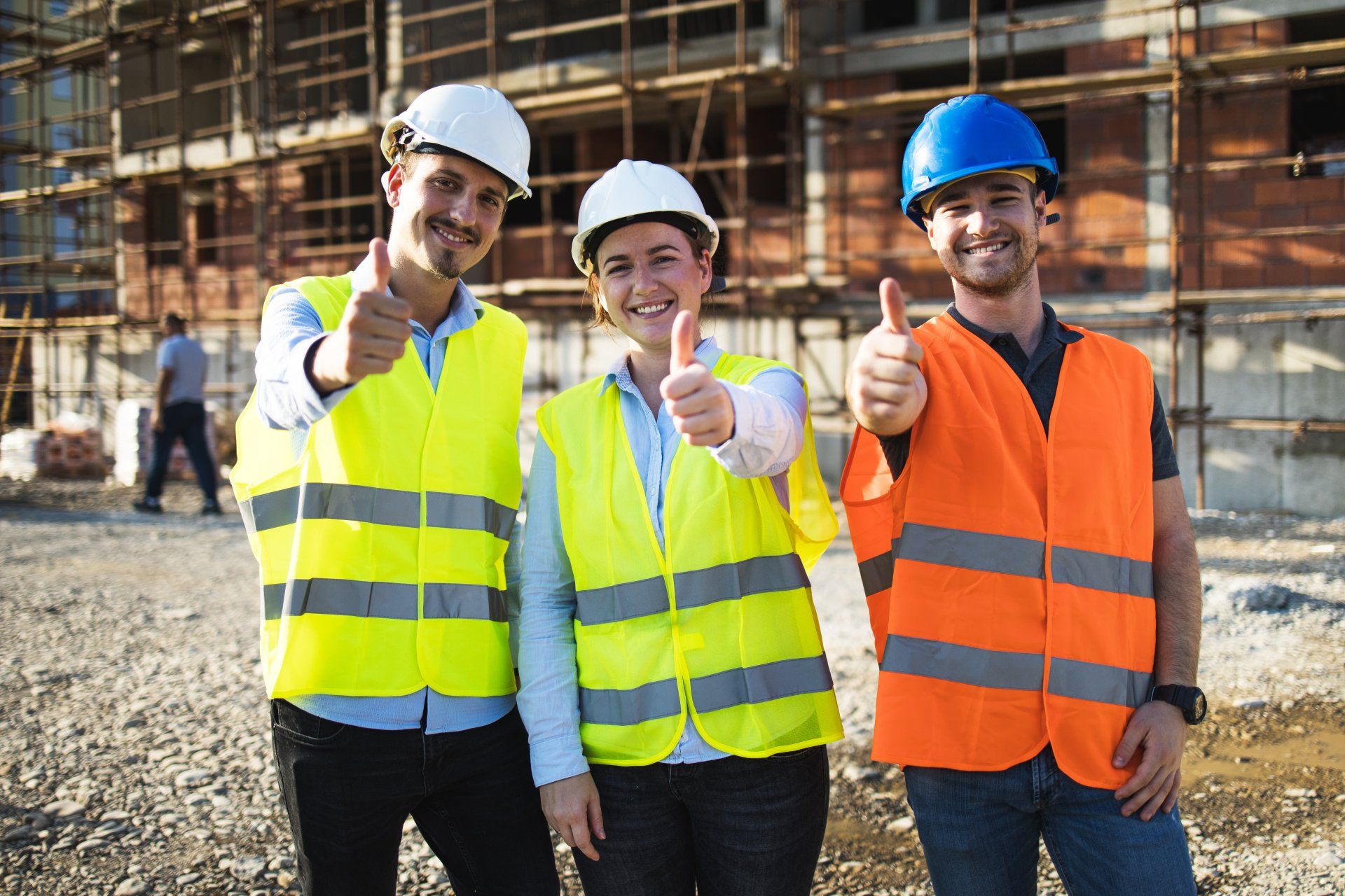 A group of construction workers are giving a thumbs up at a construction site.