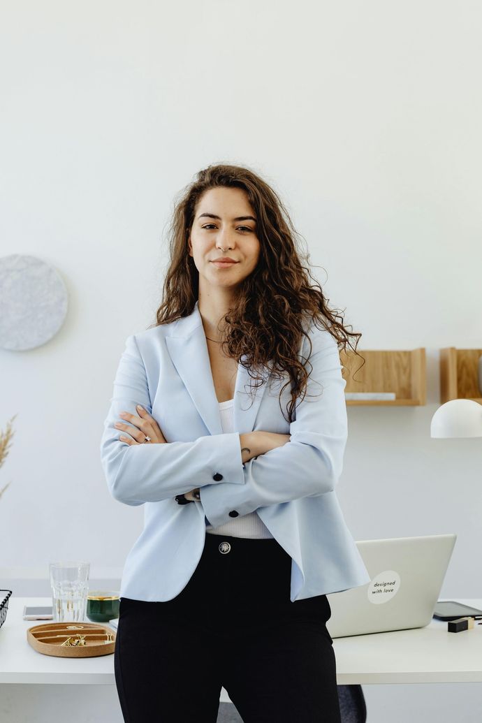 Woman smiling at desk with computer, cameras, and drawing tablet.