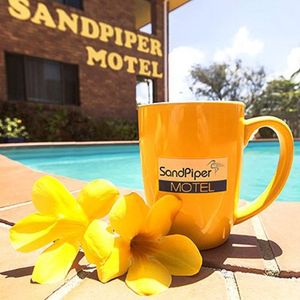 flowers and mug in front of sandpiper motel sign