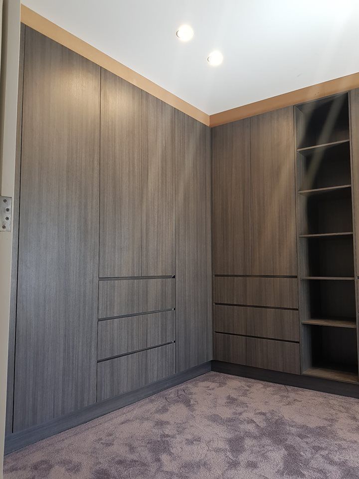 Built-in grey wood closet with three drawers, open shelving, and light wood trim, in a room with a light purple carpet — Protech Renovations & Joinery in Gregory Hills, NSW