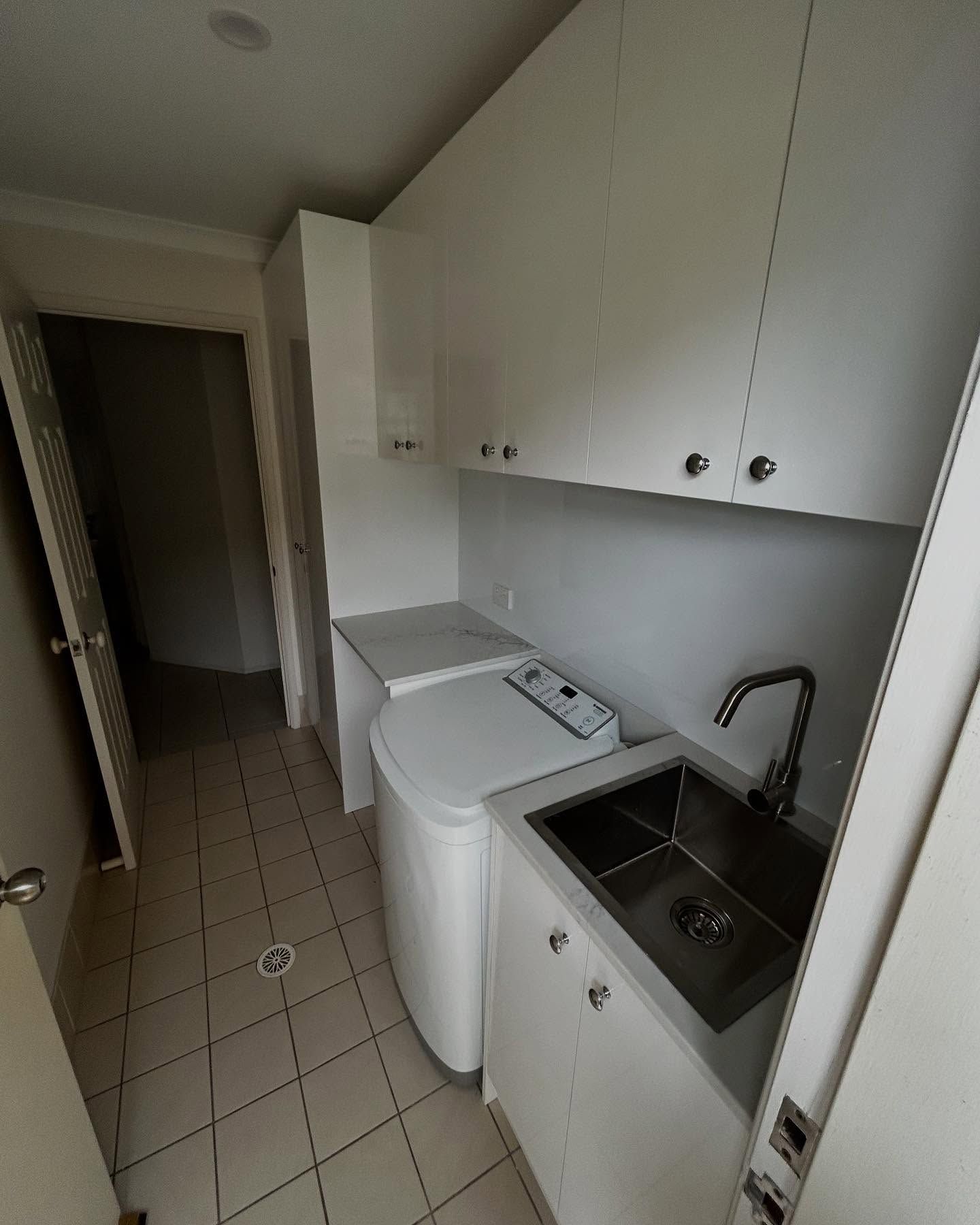Laundry Room With White Cabinets, Washing Machine, Sink, And Tiled Floor — Protech Renovations & Joinery in Wollongong, NSW