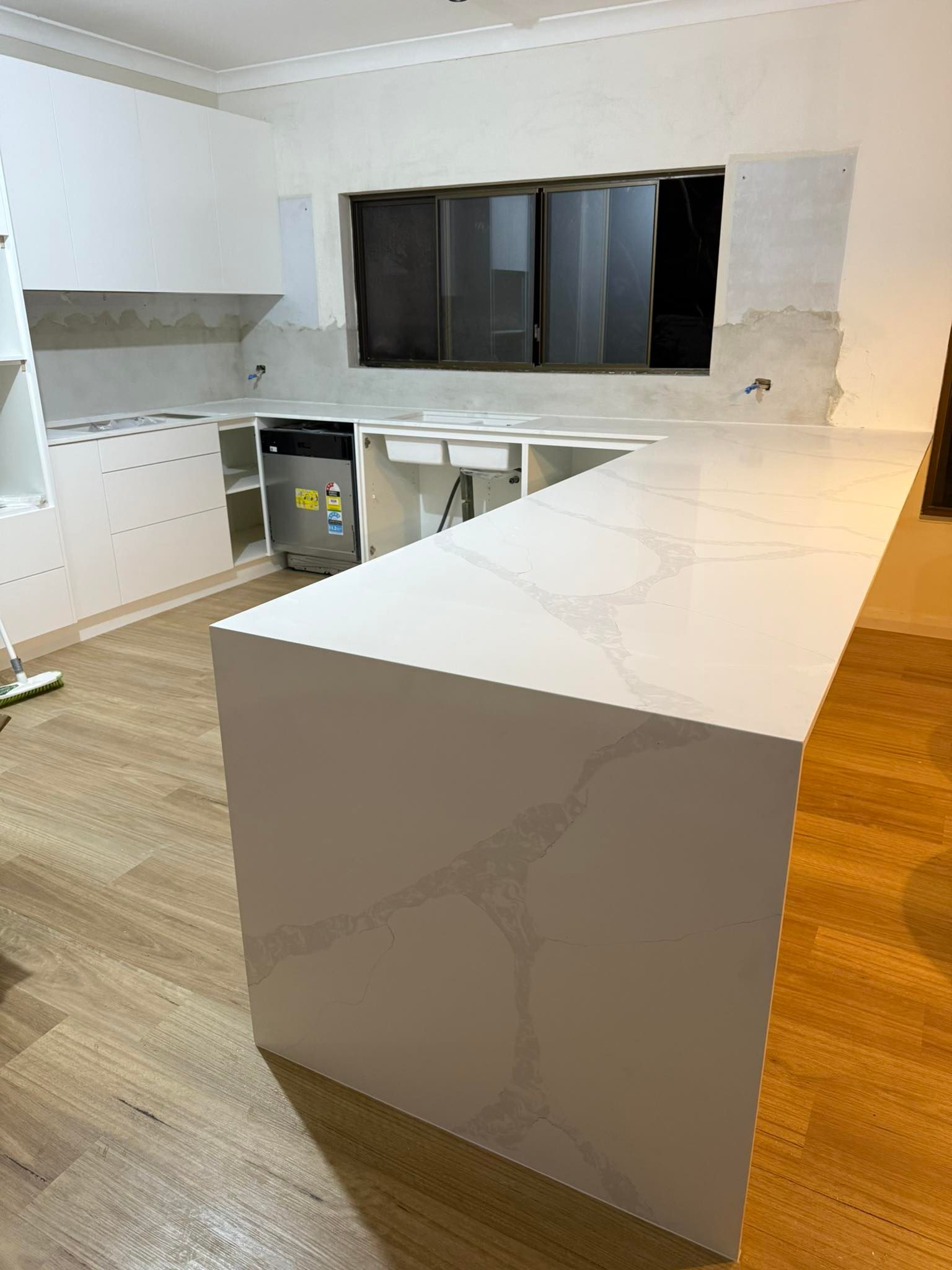 White Kitchen Island With Quartz Countertop In Partially Renovated Kitchen — Protech Renovations & Joinery in Narellan, NSW