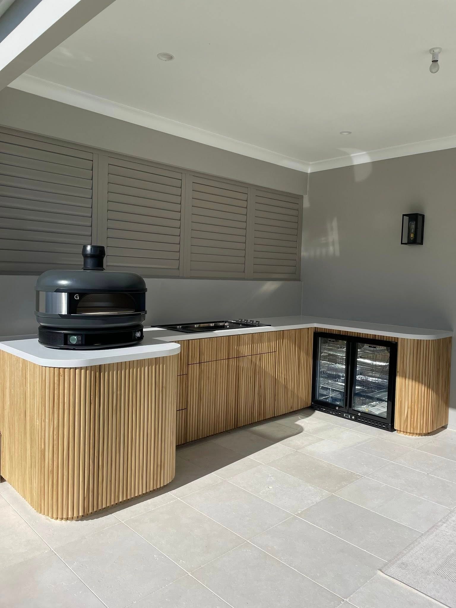 Outdoor Kitchen With Pizza Oven, Wine Fridge, And Wood-Textured Cabinetry — Protech Renovations & Joinery in Campbelltown, NSW