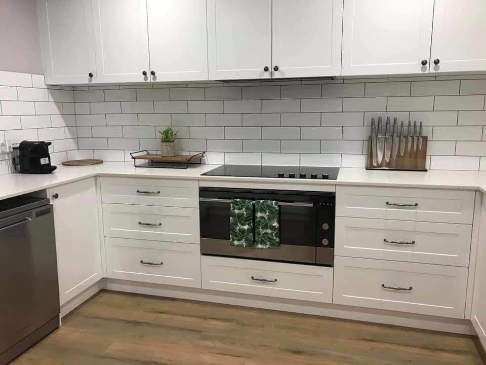 Modern kitchen with wood cabinets, white countertops, and a dishwasher. Island with drawers — Protech Renovations & Joinery in Gregory Hills, NSW