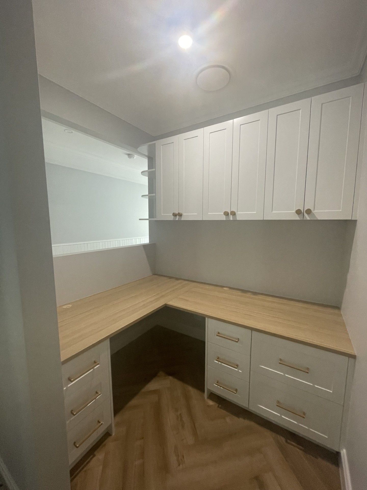 L-shaped home office with light wood desk, white cabinets, and built-in upper shelves — Protech Renovations & Joinery in Gregory Hills, NSW
