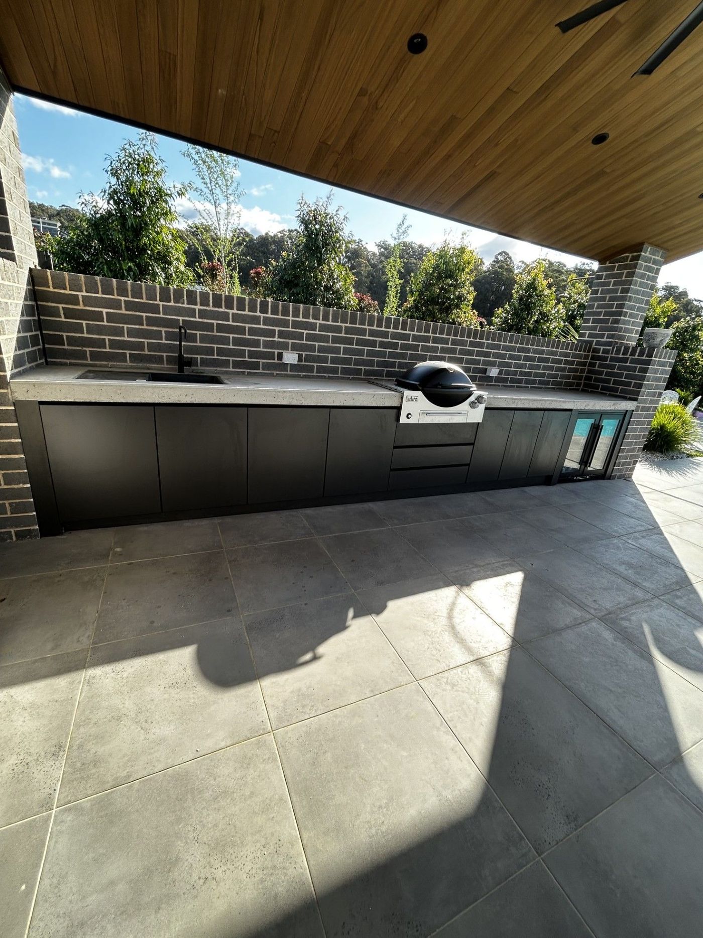 Outdoor kitchen with a grill, cabinets, and a brick wall — Protech Renovations & Joinery in Gregory Hills, NSW