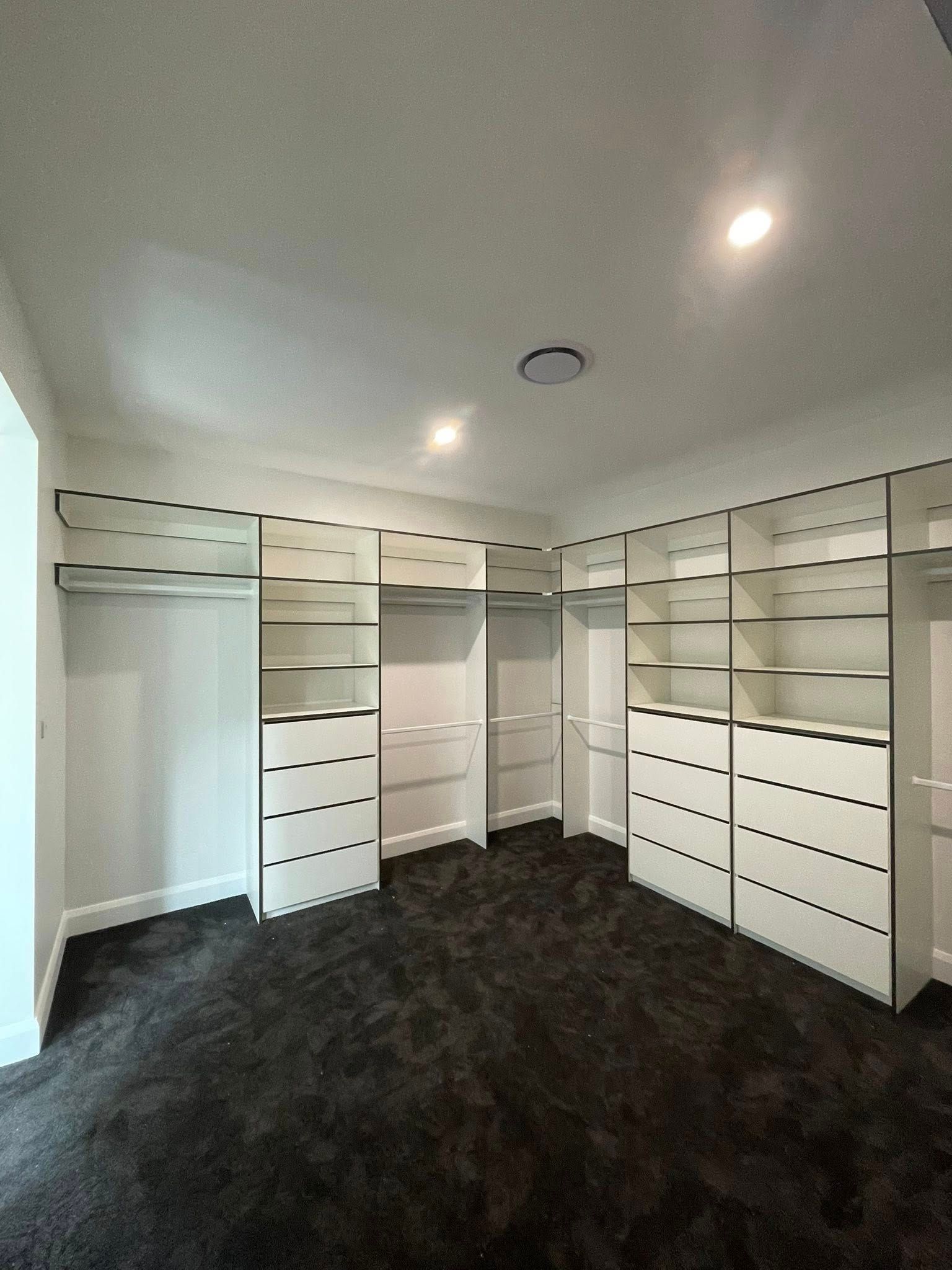 Walk-in closet with white shelves and drawers, dark grey carpet — Protech Renovations & Joinery in Gregory Hills, NSW
