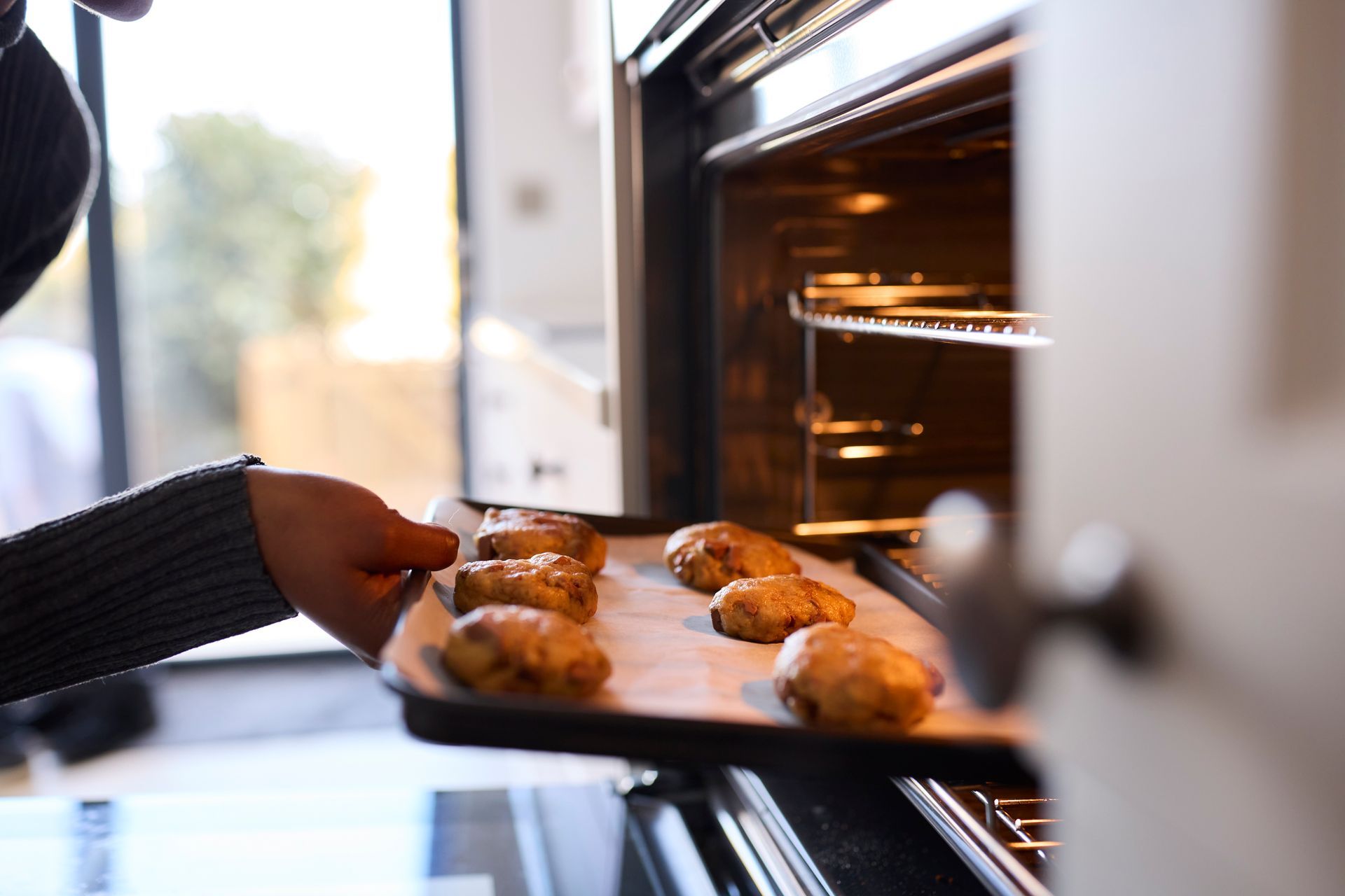 close up of woman putting baking tray inside an oven