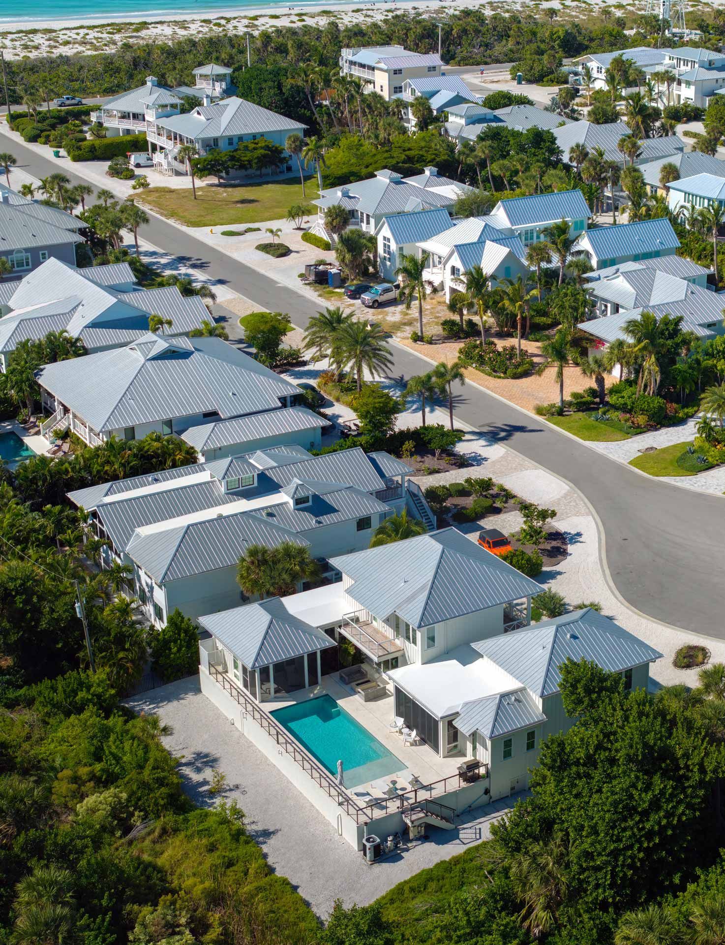 Aerial view of houses with light blue roofs near a beach and ocean.