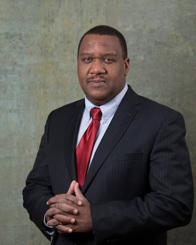 A man in a suit and tie with his hands folded