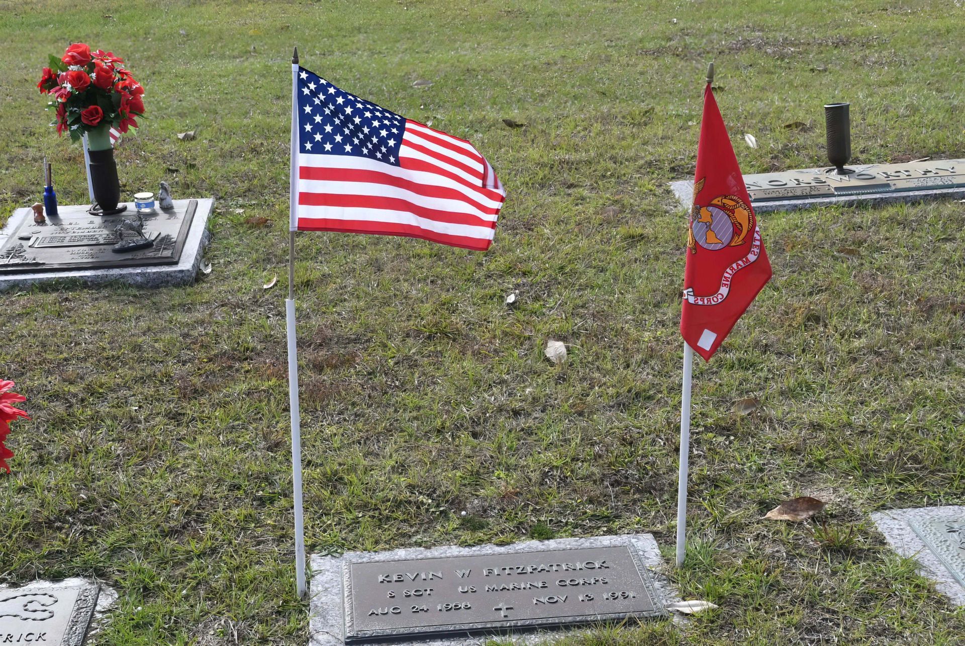 An american flag and a red flag are in a cemetery