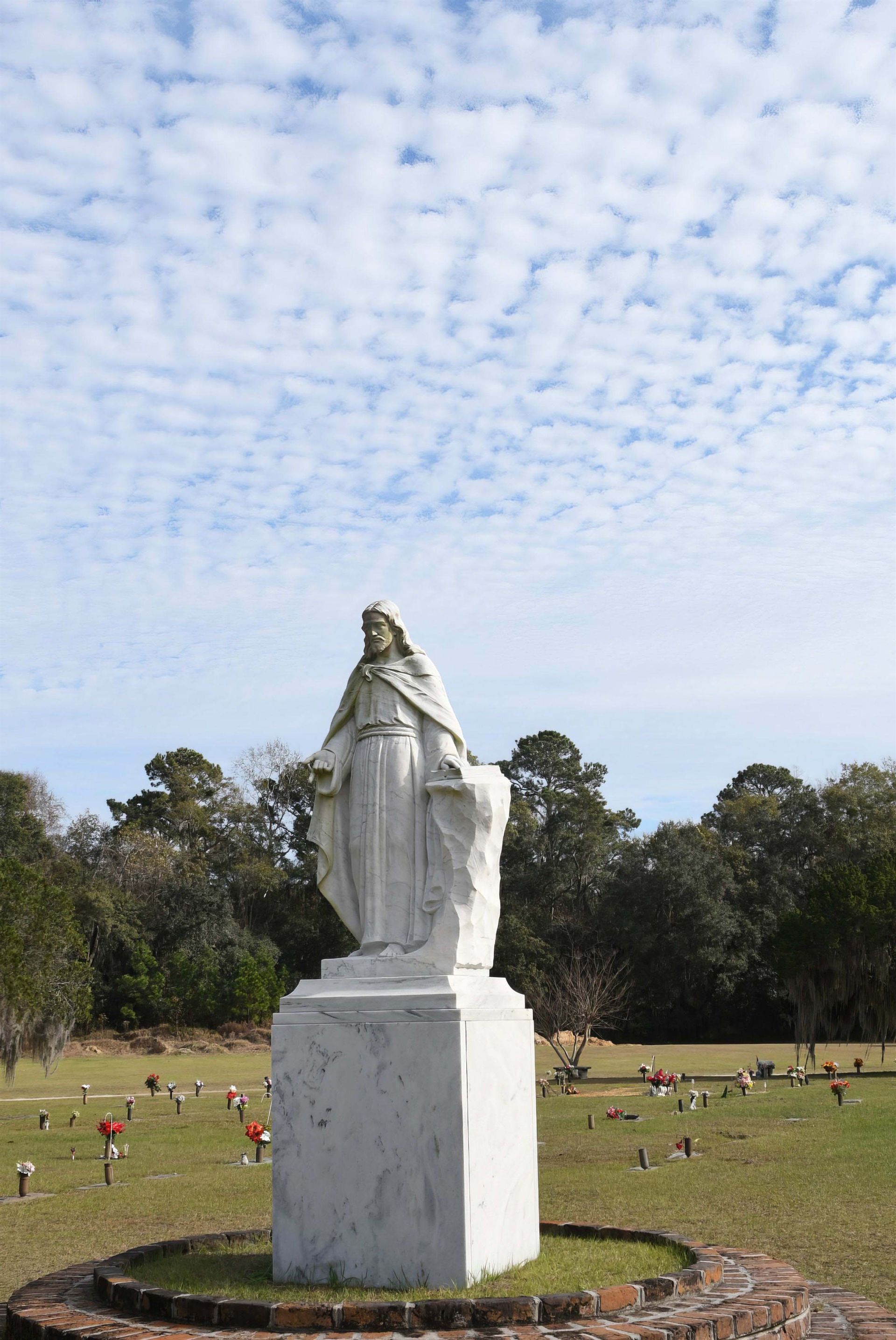 A statue of a woman standing on a pedestal in a cemetery.