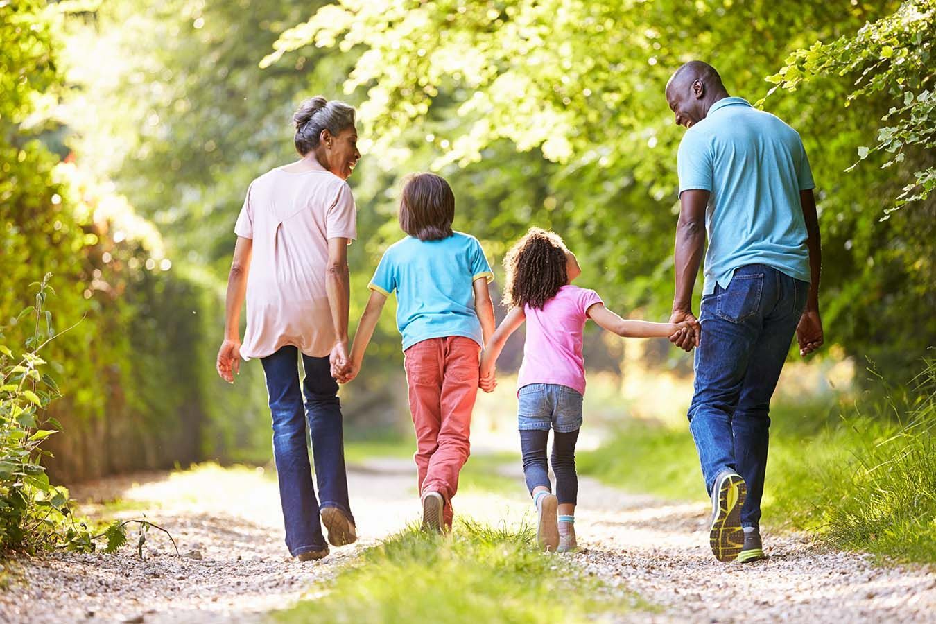 A family is walking down a dirt path holding hands.