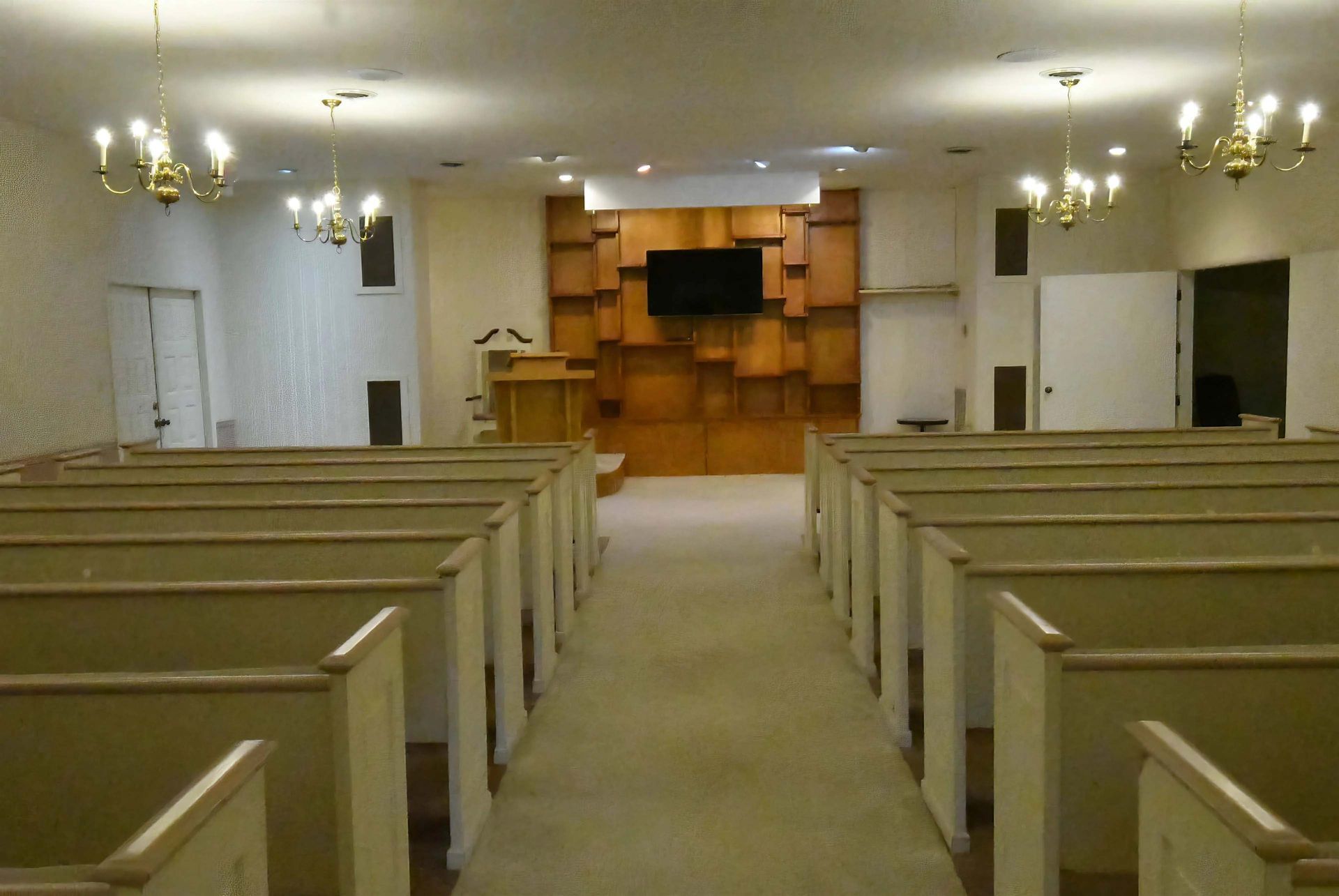 A church with rows of benches and a flat screen tv on the wall