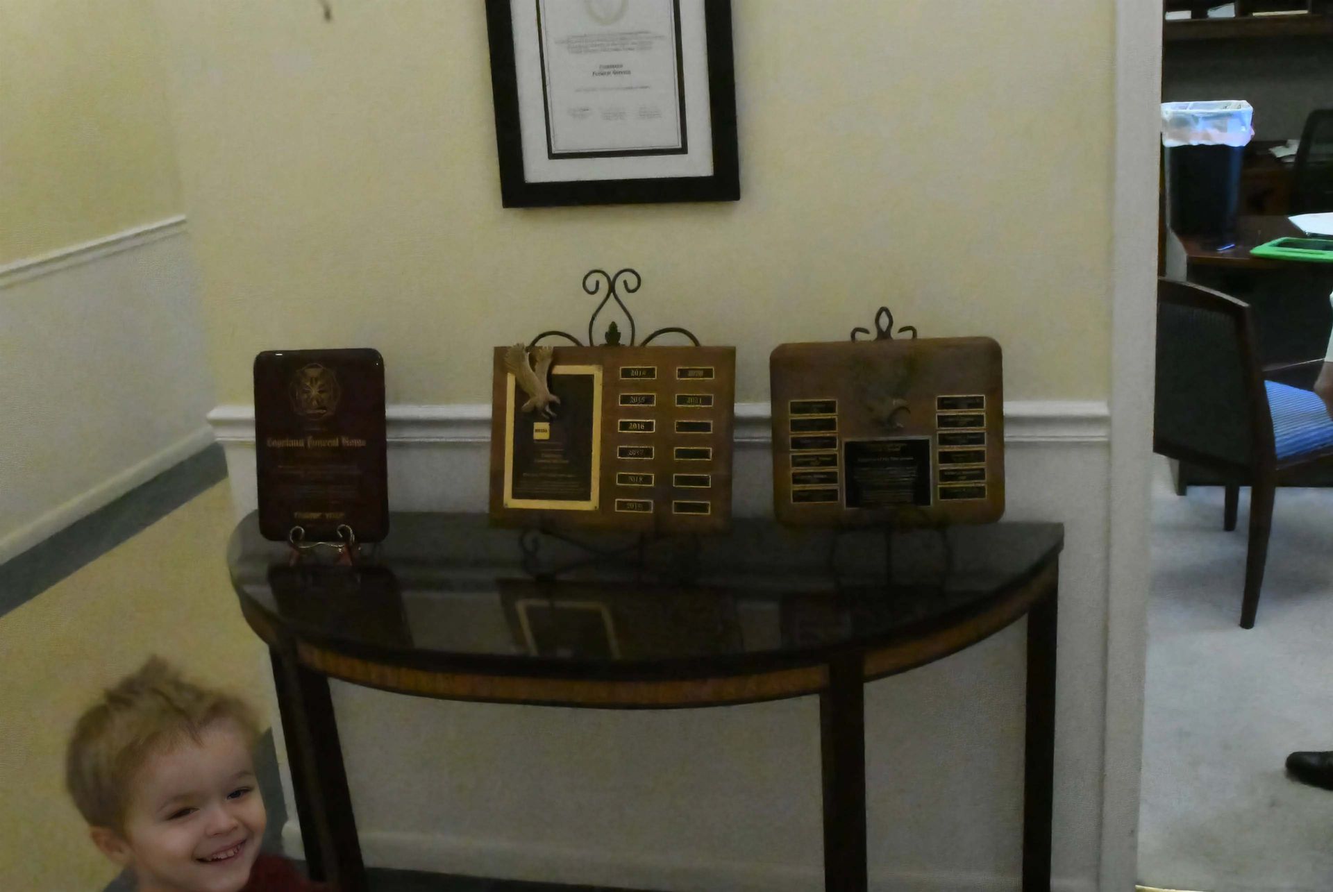 A little boy stands in front of a table with plaques on it
