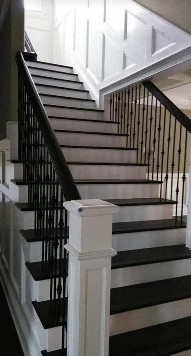 Staircase with dark treads and white risers, black railing with decorative spindles, and white paneled walls.