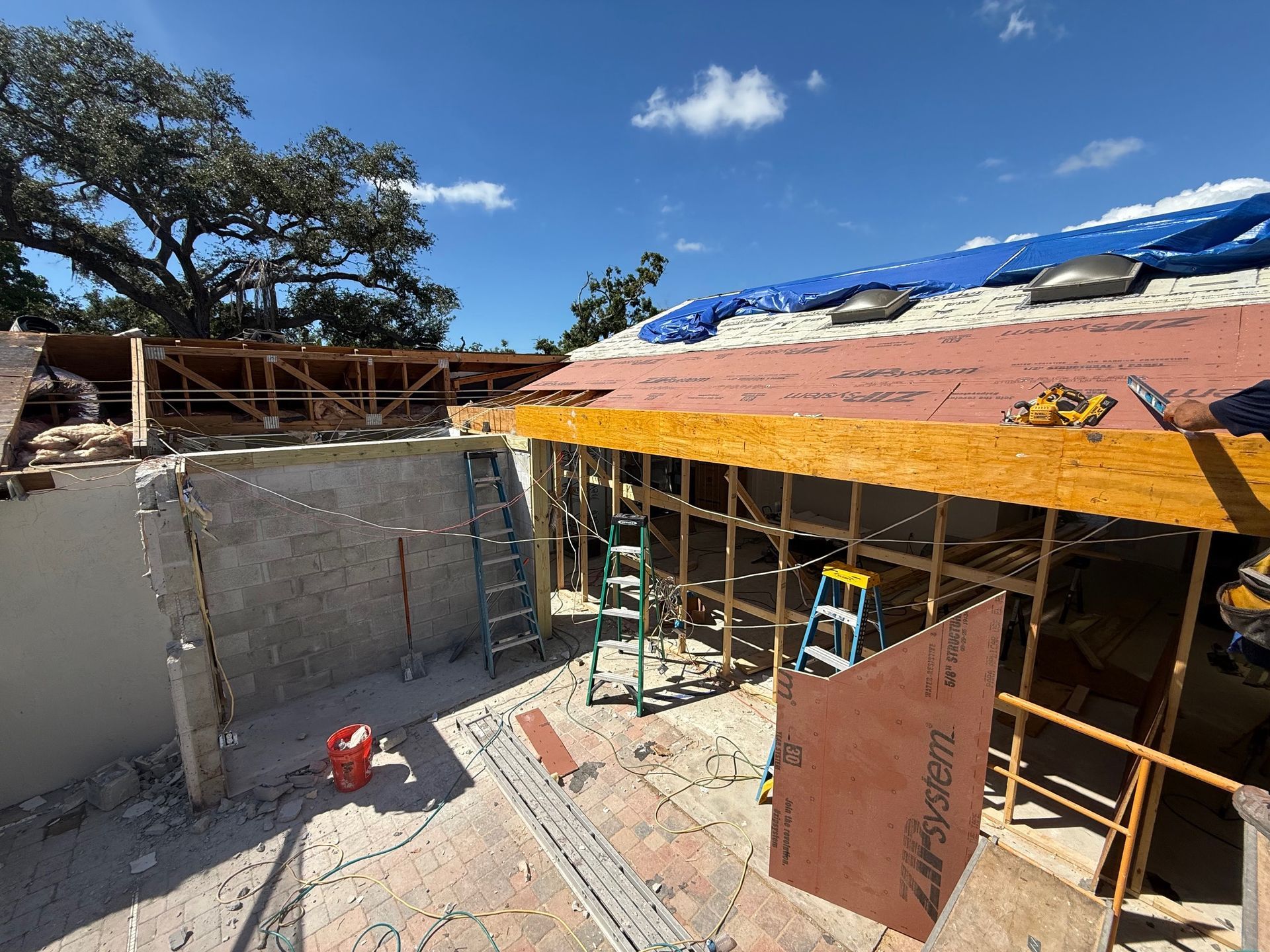 Construction site with partially built roof and exposed framing, clear sky.
